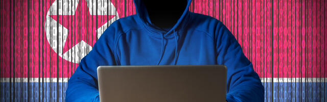 Hacker met een laptop voor zich en de Noord-Koreaanse vlag achter zich
