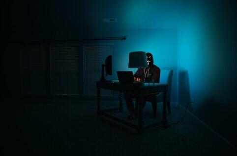 Een hacker die in het donker achter de computer zit