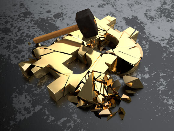Een hamer vebrijzelt een Bitcoin logo