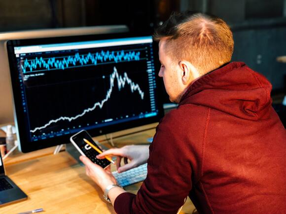 Jongen zit voor computer en kijkt naar trading scherm