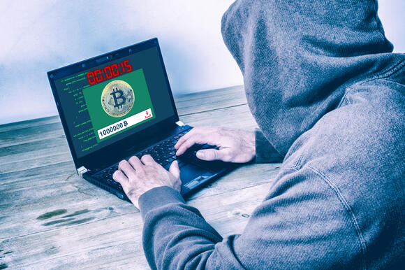 Achterkant van hacker met hoodie die crypto aan het stelen is