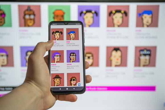 Mobiel met pc in de achtergrond en alletwee hebben CryptoPunks op hun scherm