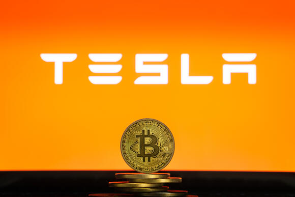 Bitcoin met het Tesla logo op oranje achtergrond