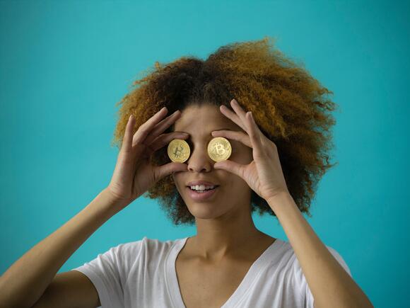 Een vrouw die fysieke Bitcoin munten voor haar ogen houdt.