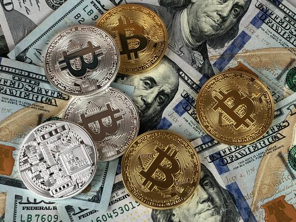 Bitcoin munten met op de achtergrond Amerikaanse Dollars.