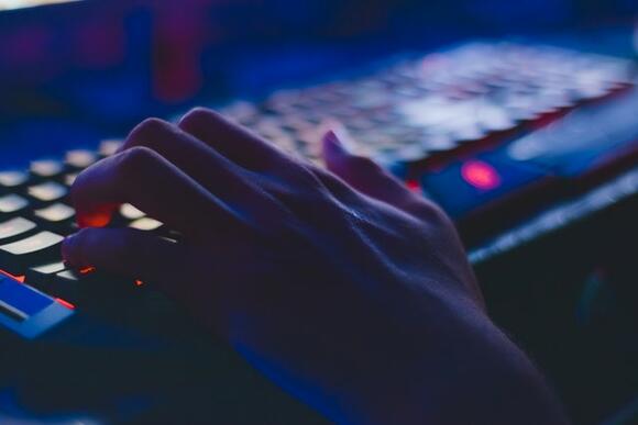Een hand die op een toetsenbord ligt, klaar om aan de slag te gaan met crypto gaming.