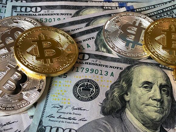 Diverse dollarbiljetten en fyieke cryptomunten.