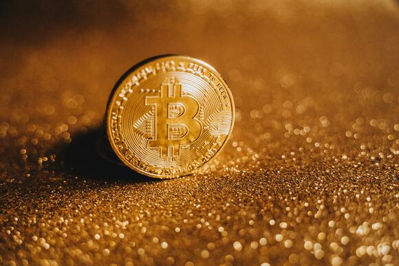 Bitcoin als fysieke munt, omringt door gouden elementen.